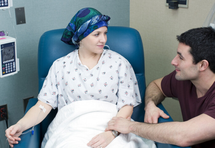 Woman with breast cancer receiving Chemotherapy; caregiver looking on.