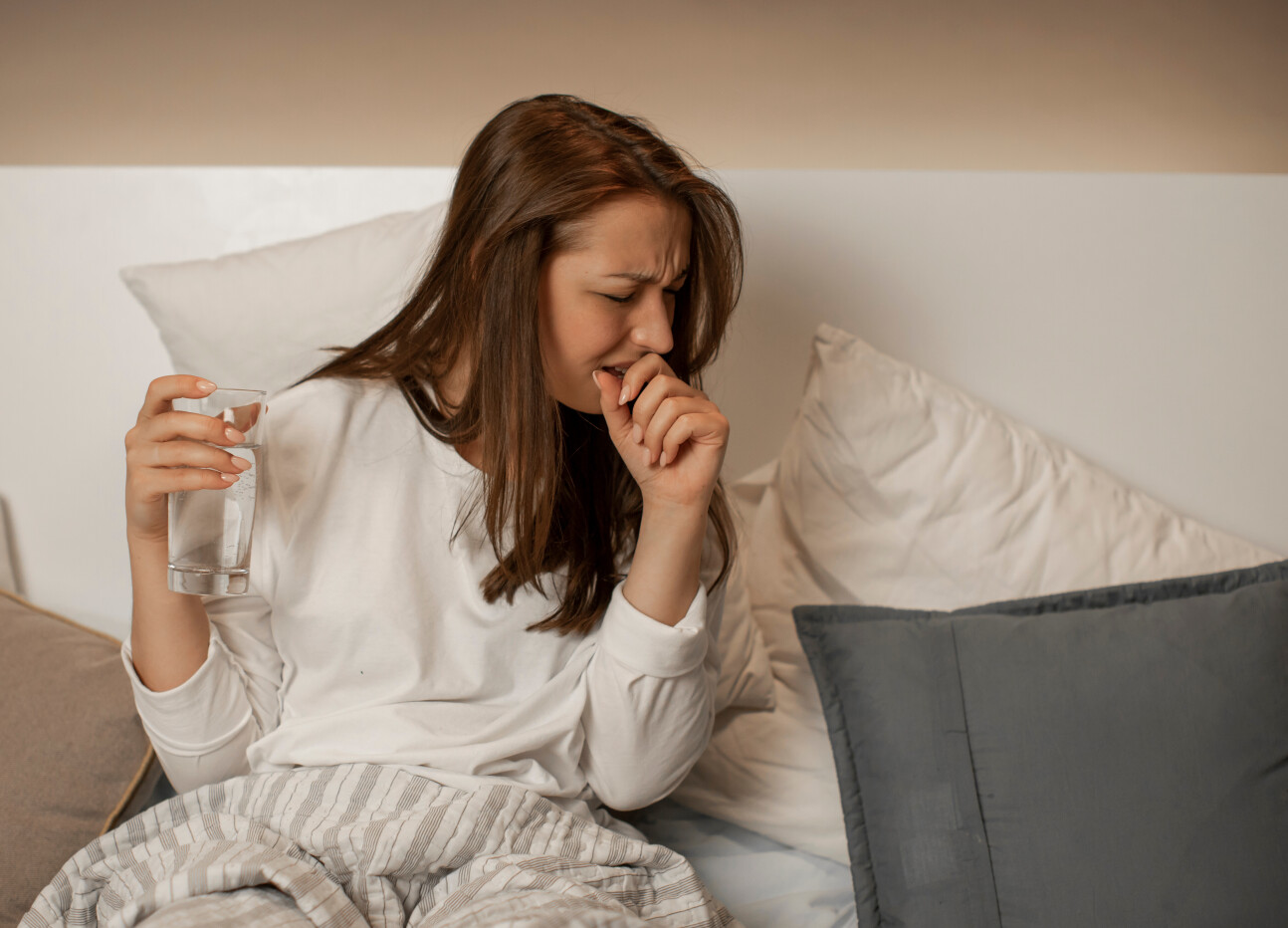 A woman in bed coughing
